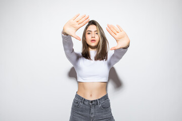 Serious young woman showing stop gesture over white background