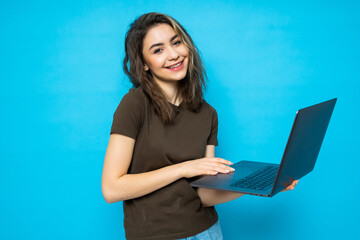 Wall Mural - Portrait of a happy beautiful girl with laptop isolated over blue background