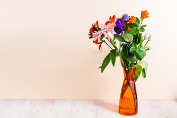 Wall Mural - floral composition with bouquet in orange vase on wooden surface on beige background