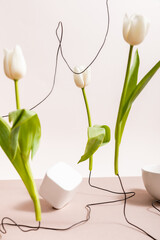 Poster - selective focus of creative floral composition with tulips on wires, cup and square cube isolated on beige