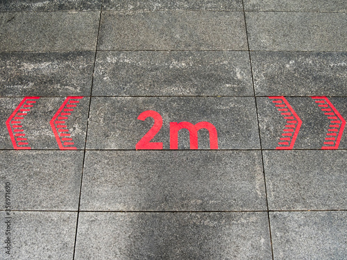 Social distancing floor sign, painted red arrow signs and 2m distance or 6 feet. East London. Covid-19, Coronavirus lockdown. Copy text space.