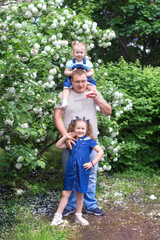 Two small daughters prepared a gift for their father on a birthday or family day. A happy father on a walk with two daughters in the Park on a Sunny spring or summer day. Concept of family happiness