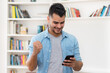 © Daniel Ernst - Cheering hispanic hipster man in quarantine shopping online with mobile phone