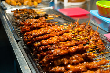 Wall Mural - Asian food. A counter with mini kebabs of chicken skin and meat at a nightly street food market.