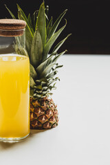 Canvas Print - fresh pineapple juice in bottle near cut delicious fruit on white surface isolated on black