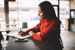 © BullRun - Cheerful afro american female student writing homework in cafe having creative solution for task