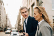 © Maskot - Side view of businessman talking to female colleague in city