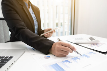 Close up hand of business woman is analyzing business income with graph for planning strategy.