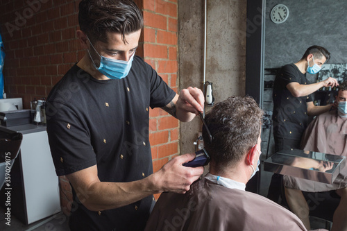 Fotomural Peluquero cortando el pelo a cliente, ambos con la mascarilla de protección por