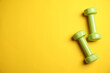 © New Africa - Top view of modern green dumbbells on yellow background, space for text. Physical fitness