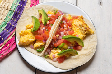 Wall Mural - Breakfast egg tacos with flour tortilla and fresh sauce on white background