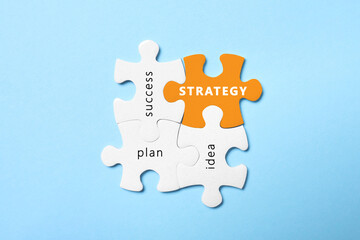 Business concept. White puzzle pieces with different phrases on light blue background, flat lay