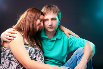 Family and Relationships Concepts. Portrait of Pregnant Woman Together with Her Husband Sitting Together Embraced. Against Black.