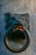 An iron lion head with a big ring in the mouth and a red padlock,  