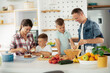 © JustLife - Mother and father making breakfast with sons. Young family preparing delicious food in kitchen.