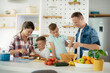 © JustLife - Mother and father making breakfast with sons. Young family preparing delicious food in kitchen.