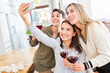 © Robert Kneschke - Freundinnen mit Rotwein machen Selfie zusammen in Küche