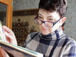 © Irina Krasnova - A middle-aged woman at the window flips through an album and looks out from under her glasses