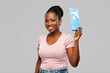 travel, tourism and vacation concept - happy young african american woman with air ticket over grey background