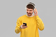 © Syda Productions - music, technology and people concept - smiling young man with headphones and smartphone over grey background