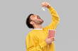 fast food people concept - young man in yellow sweatshirt eating popcorn throwing it to open mouth over grey background