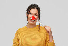 Red Nose Day, Party Props And Photo Booth Concept - Portrait Of Happy Smiling Young Woman With Clown Nose Over Grey Background