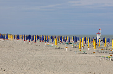 Wall Mural - beach with few people and closed sun umbrellas due to the terrib