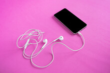 Black Phone And White Headphones On A Bright Pink Background.
