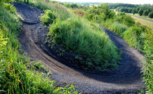 single trail path on mountain sprung bikes sharp bends bends jumps in forest or meadow. dark gravel on the ground racetrack jumps enduro motocross city park public sports ground