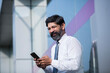 © G-images - A portrait of businessman with smartphone standing outside the office