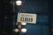 © Looker_Studio - sorry we are closed sign hanging outside a restaurant, store, office or other. Closed sign in a shop showroom with reflections bokeh.