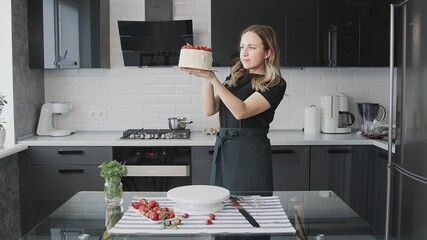 Cooking cake at home. Young attractive housewife finished cooking the cake and admiring it