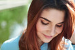 close-up of the face of a young shy girl. a young girl with red hair smiles, looks down and is shy