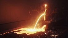 Magical Beautiful View Of Hot Molten Metal Stream Coming Out Of The Furnace, Sparks, Lights, Steel Production Plant, A Pool Of Liquid Metal. Slow Motion Shot.