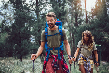 Backpackers couple hiking during fall with sticks