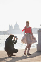 Man videoing smiling woman at waterfront in Venice