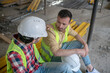 © zinkevych - Tired building workers in yellow vests sitting on boards, one of men putting his hand on coworker shoulder