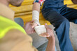© zinkevych - Close-up of building worker hands applying bandage on his coworker forearm