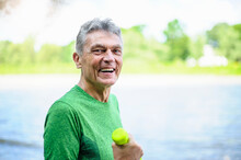 Side View Portrait Of Smiling Active Senior Man Exercising In Park