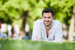 © Westend61 - Portrait of smiling young man lying on blanket in park