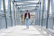 © Westend61 - Young man walking on a bridge with earbuds and smartphone