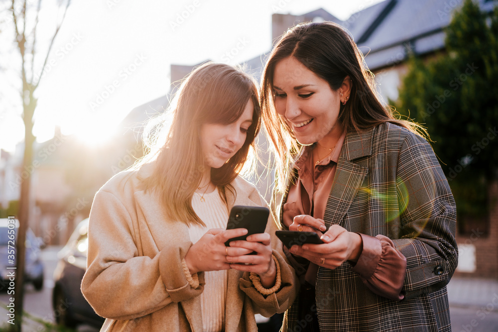 Portrait of two best friends looking at cell phone at backlight