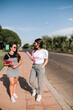 © Westend61 - Full length of smiling young female students holding files while walking on footpath at university campus against sky