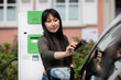 © Westend61 - Carsharing, woman renting an electric car using smartphone