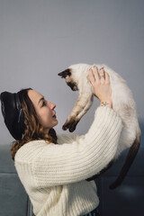 Wall Mural - Lovely woman playing with Siamese cat at home. Friendship between humans and animals