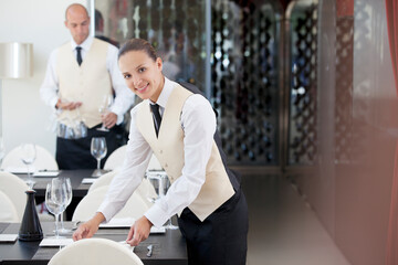 Waitress setting table in restaurant