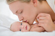 © Tom Merton/KOTO - Mother kissing newborn baby on bed