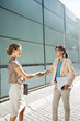 © Robert Daly/KOTO - Businesswomen shaking hands on city street