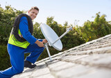 Worker installing satellite dish on roof