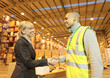 © Paul Bradbury/KOTO - Businesswoman and worker shaking hands in warehouse